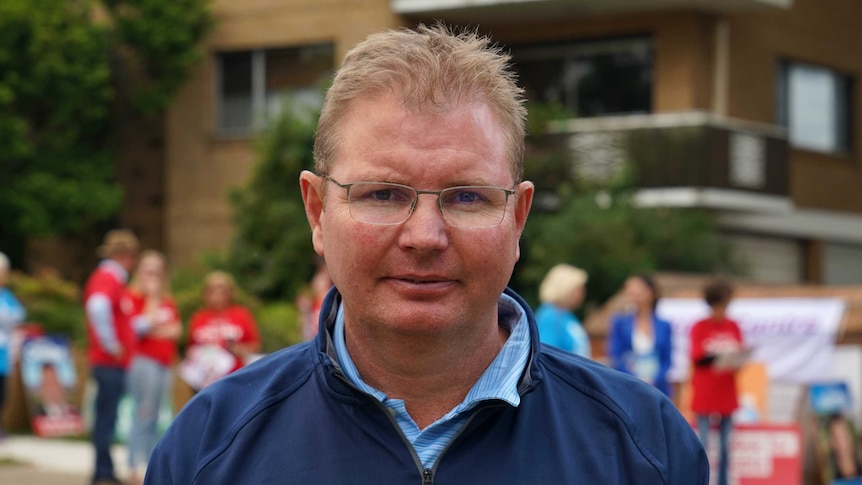 Mr Laundy stands in front of a group of political campaigners.