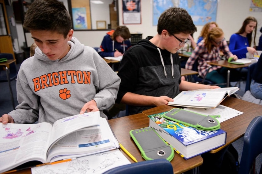 Students in a classroom with lockable Yondr phone pouches.