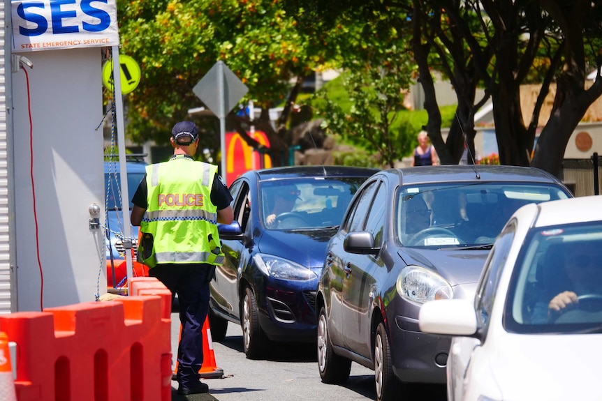 Cars lined up and a police officer on the border between New South Wales and Queensland