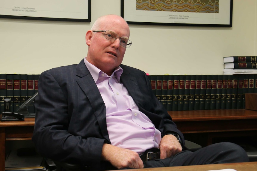 Melbourne barrister Julian McMahon sits in a chair.