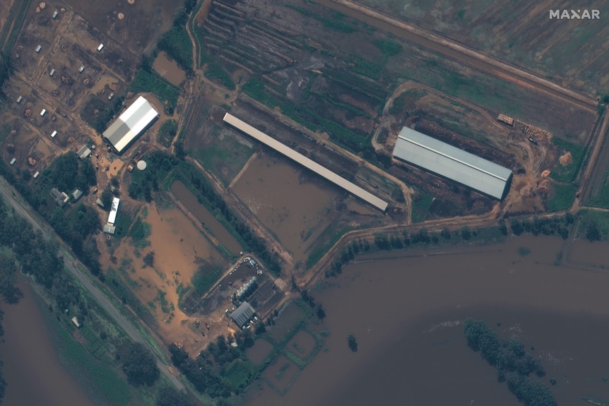 A picture from above of a farm under brown floodwater 