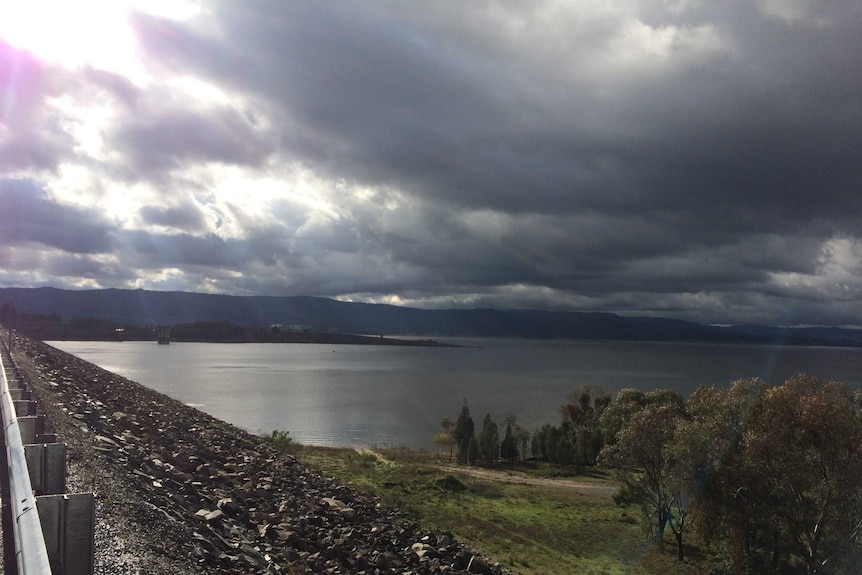 A large water storage dam under cloudy skies