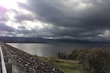 A large water storage dam under cloudy skies