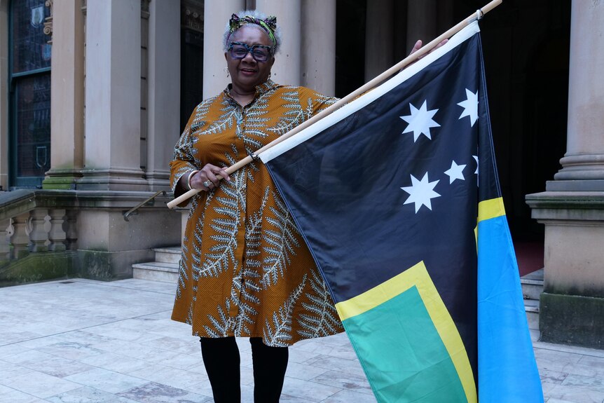 Cr (Waskam) Emelda Davis holding the Australian South Sea Islander flag at Town Hall. 