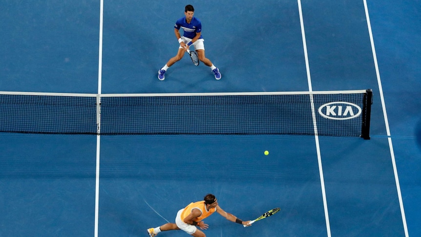 Rafael Nadal stretches for a backhand up at the net as Novak Djokovic awaits at close range during the Australian Open final
