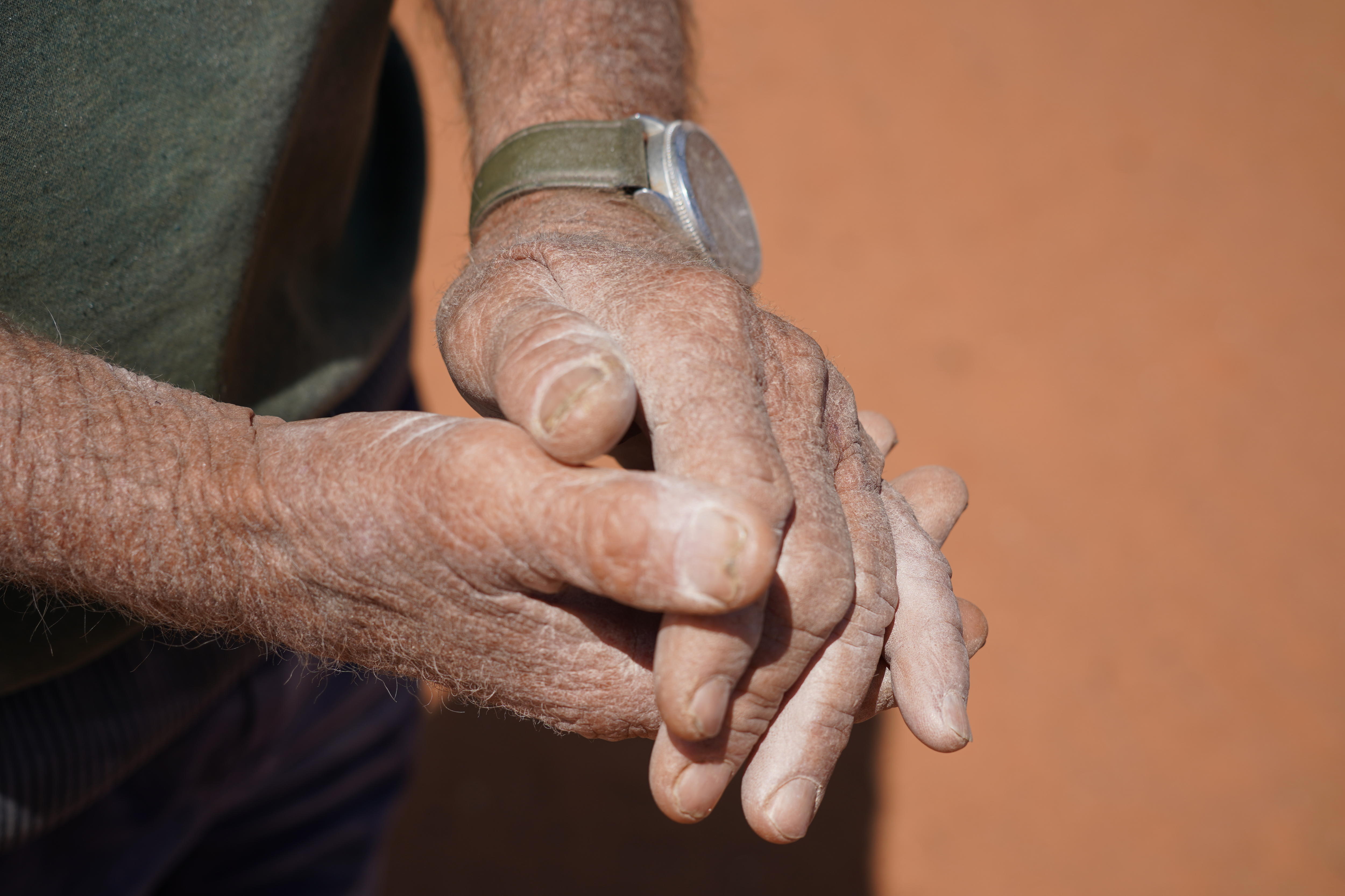Dos manos cubiertas de polvo blanco sobre un fondo arenoso. 