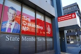 An office building showing a politician in a suit reading Tim Crakanthorp MP on the glass windows