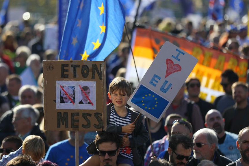A child sits on his father's shoulders holding a sign saying 'I love EU' during the people's march against Brexit.