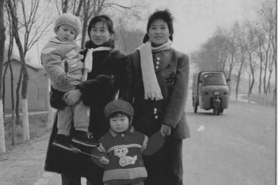 Two women and two children pose for the camera standing on a road.