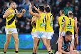 Port Adelaide players in the foreground are upset as a bunch of Richmond players celebrate behind them