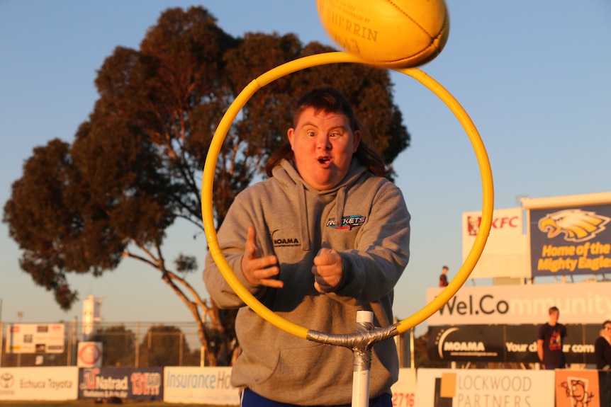 Peter Keath looking excited as he handballs a footy through a hoop.