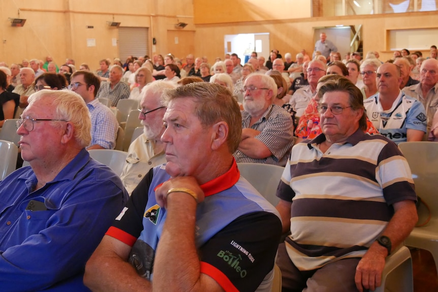 A large group of people sitting in a community hall.