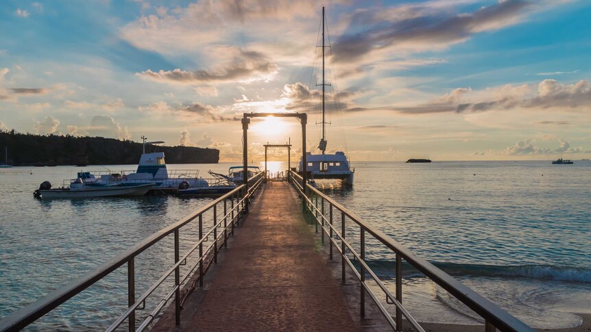 A pier with cruises over East China sea at sunset Cape Manza, Onna, Kunigami District, Okinawa, Japan.