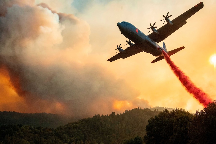 An aircraft drops fire retardant on a ridge in California