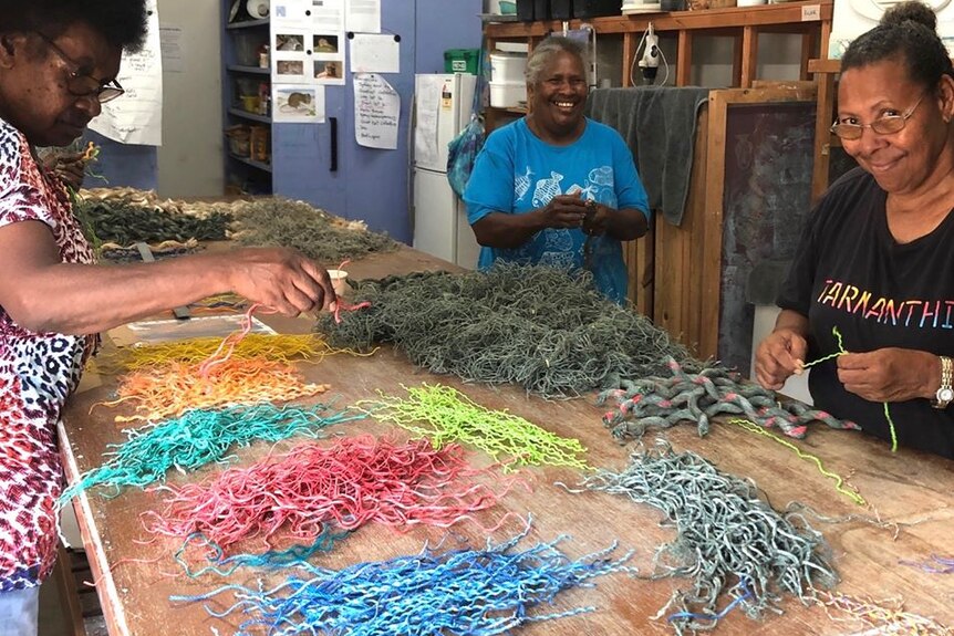 Torres Strait Islander women around a table with piles of netting and ropes of different colours