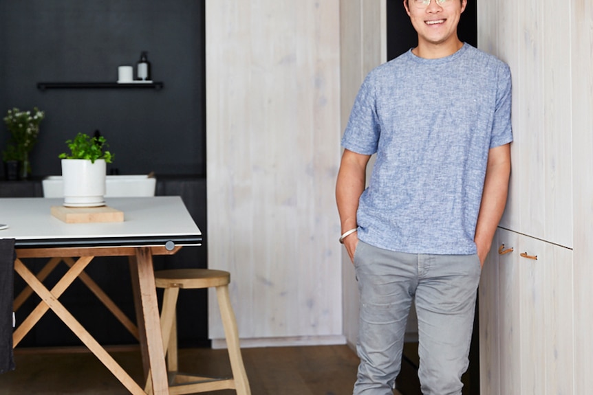 A man leans on the wall of his office, he manages indoor plants and knows how to manage common pests.