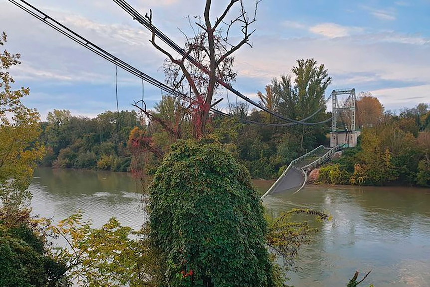 Remains of a bridge, with the road collapsed into a river.