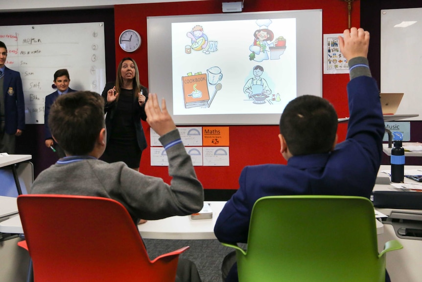 Boys at Patrician Brothers' College Fairfield raise their hands in their English class.