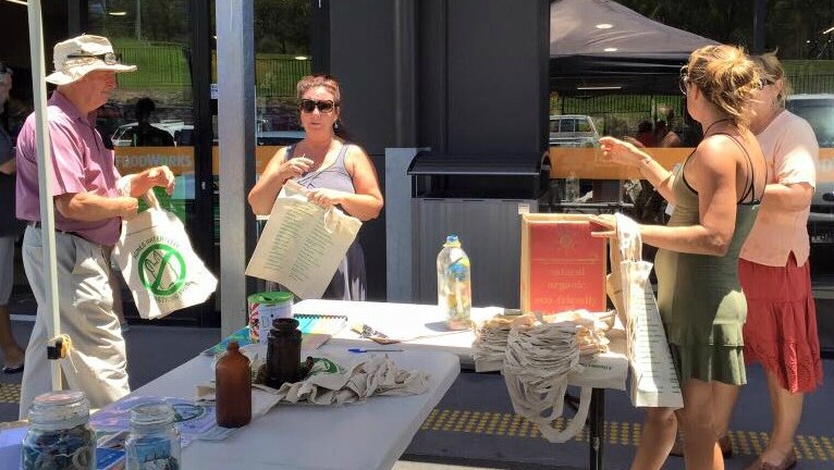 Discovery Coast Environment Group members hand out calico bags from a stall outside a supermarket
