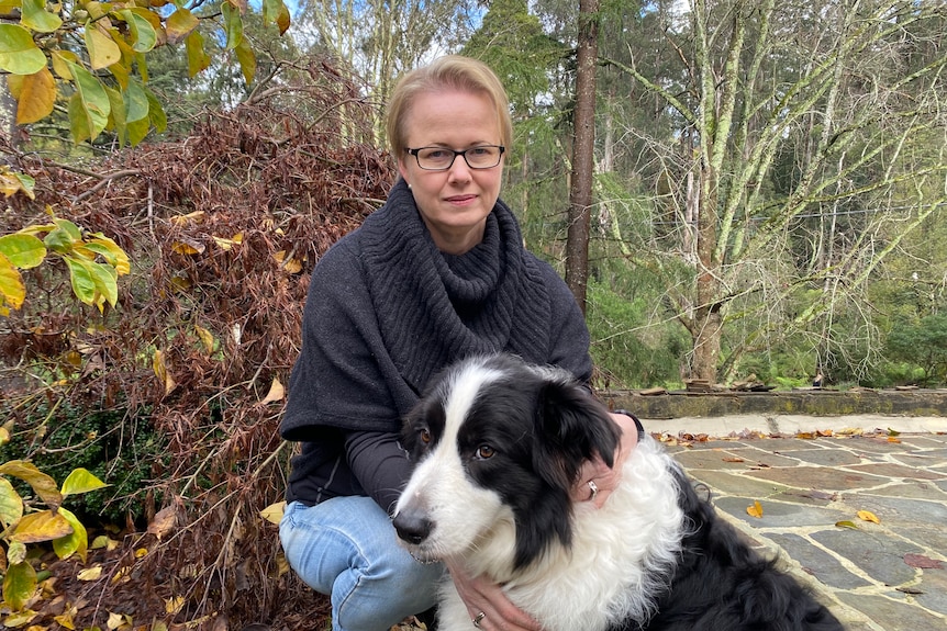 Jeanine Spink pats her border collie as she crouches at her Dandenong Ranges property.