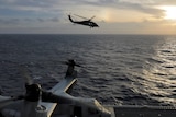 A Navy MH-60S Seahawk helicopter heads out at sunrise from an aircraft carrier..
