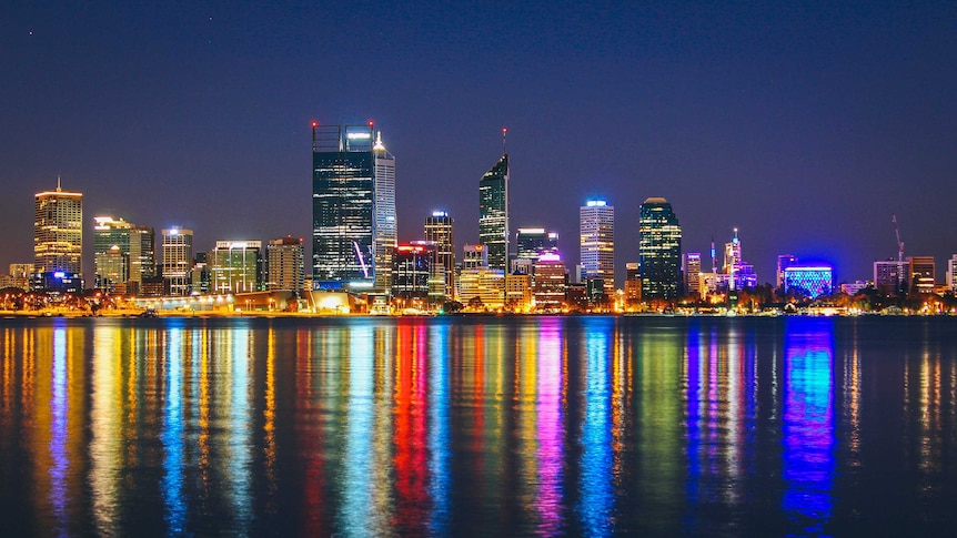 Perth city skyline at night, with bright coloured lights over the foreshore
