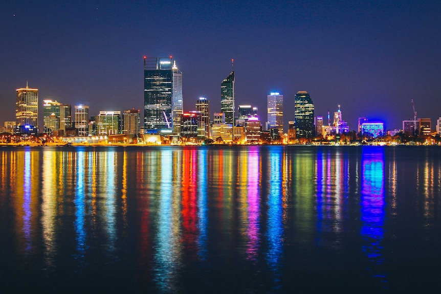 Perth city skyline at night, with bright coloured lights over the foreshore