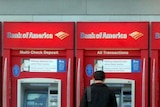 A man stands at a row of Bank of America ATM's