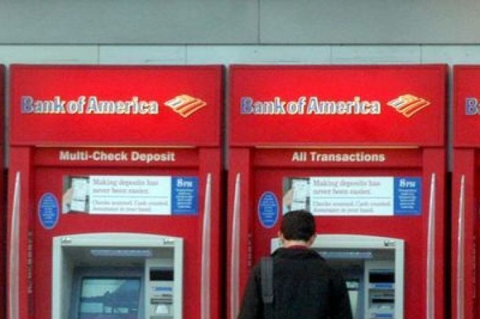 A man stands at a row of Bank of America ATMs.