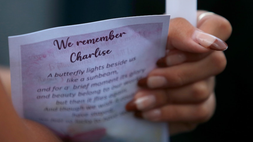 A pair of hands with french tips holds a page that reads "We remember Charlise" 