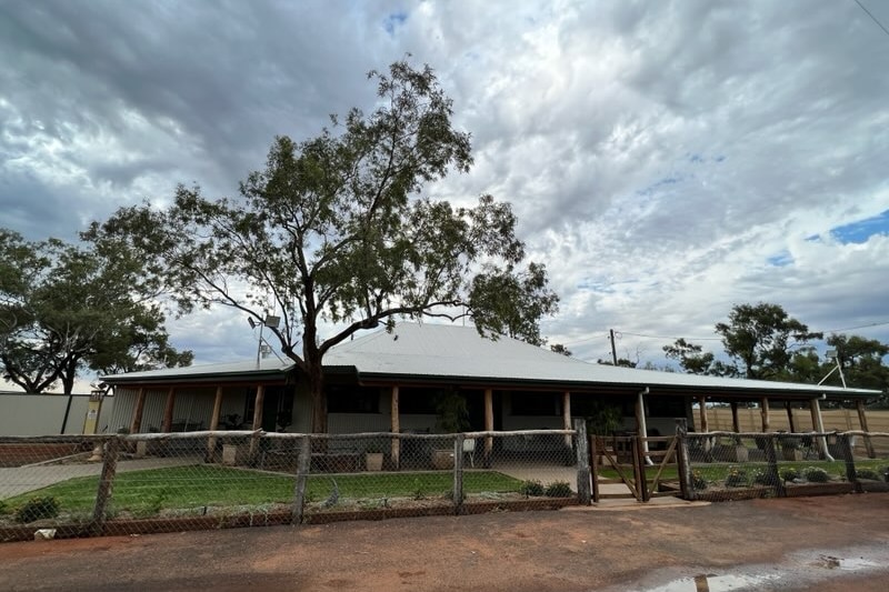 A Queenslander style pub with a large tin roof and green lawns.