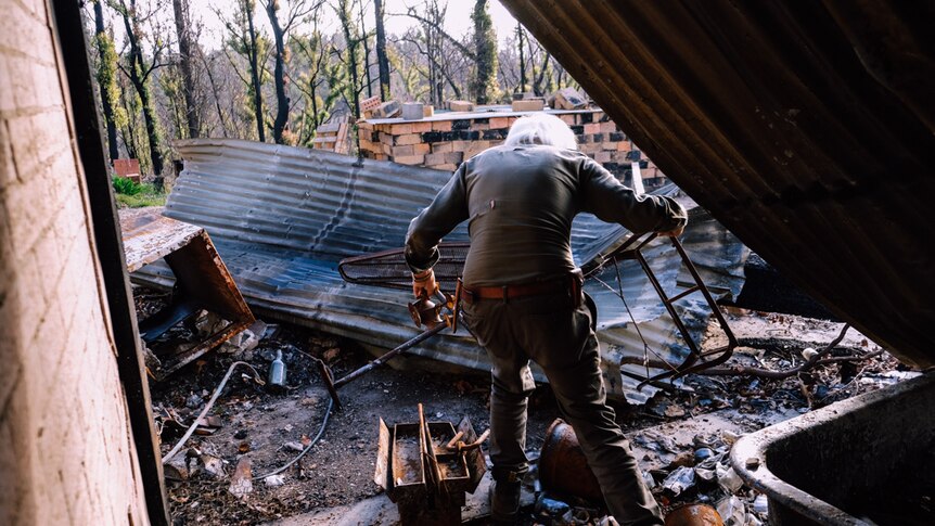 Stefan Talmatzky stumbles as he walks through his bushfire ravaged property.