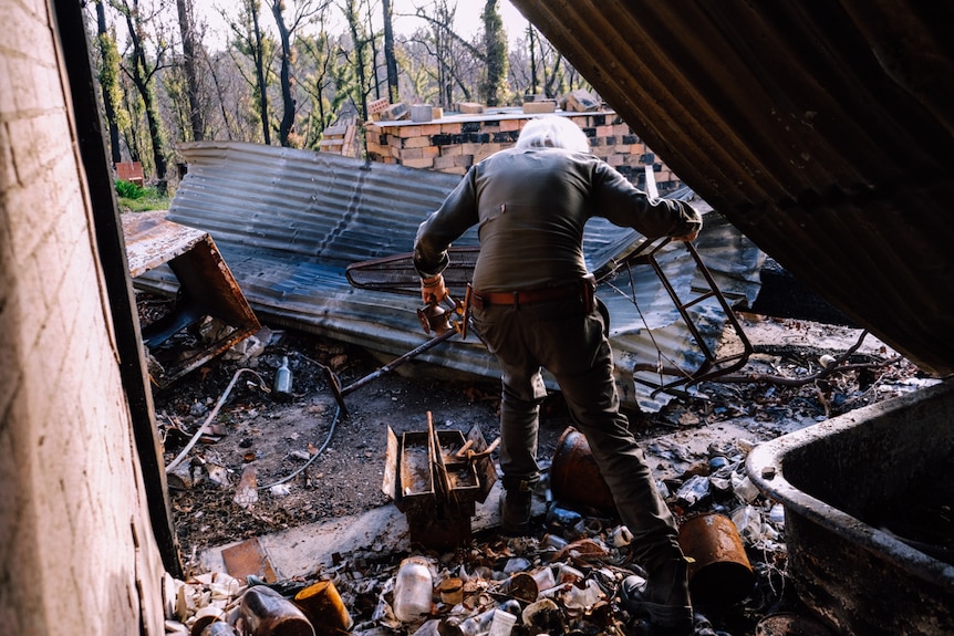 Stefan Talmatzky stumbles as he walks through his bushfire ravaged property.