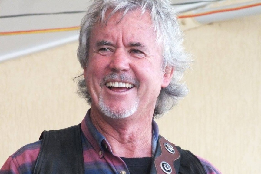 Portrait of a smiling man with grey hair and beard.