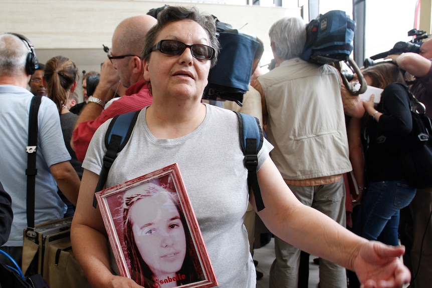 A woman holds a portrait of her daughter