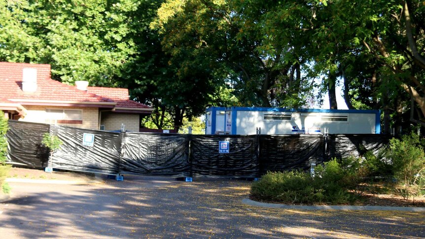 Portable fencing outside a temporary shower block in a car park.