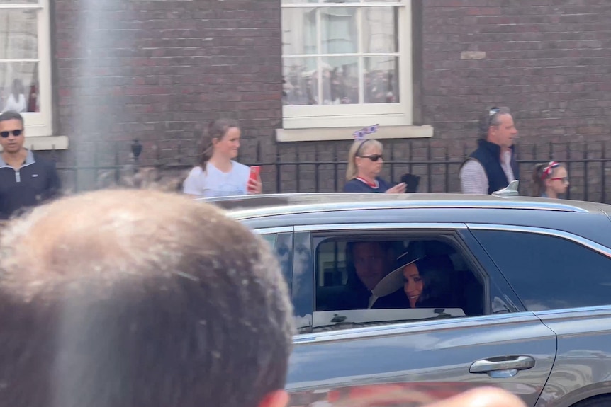 Prince Harry and Meghan inside a black car