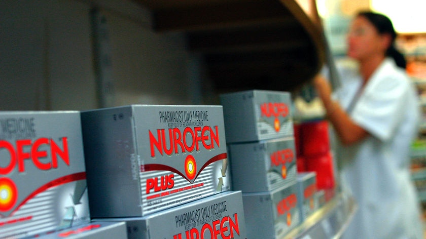 A pharmacist reaches up to Nurofen Plus packets