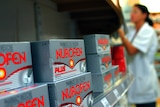 A pharmacist reaches up to Nurofen Plus packets