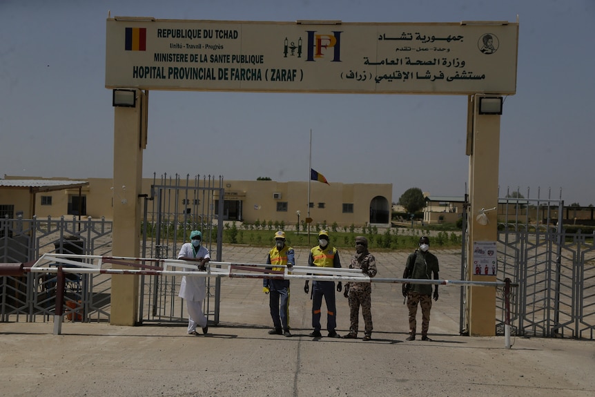 Security guards stand at a barrier outside a hospital.