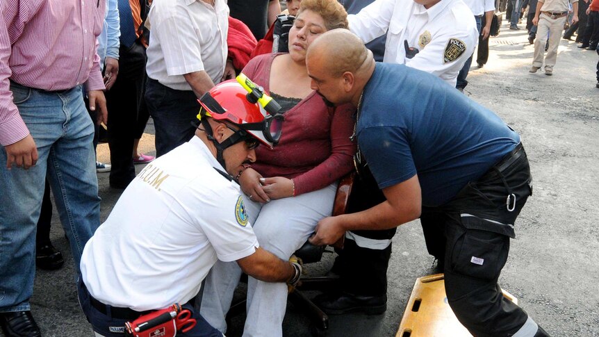 An injured woman is transferred to a stretcher outside the Pemex HQ.