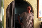 A photo of Linus Ninham standing in an archway in his breezy tropical home.