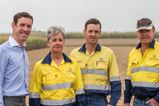 A man in a blue shirt stands next to his mother in hi vis, his brother, father and brother on a farm.