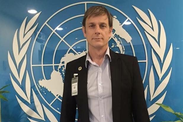 A man standing in front of the UN logo