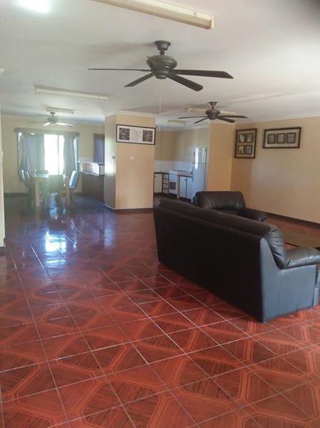 A living room with two ceiling fans, a pair of black sofas and orange walls.