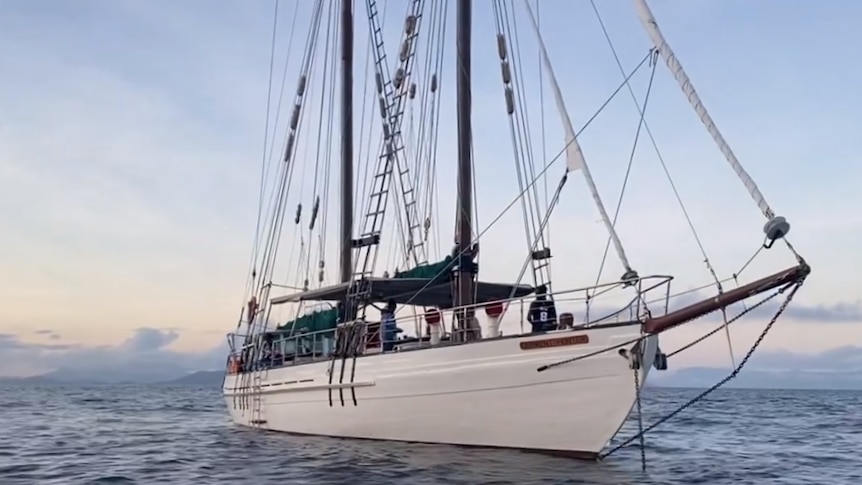 A white, long ship on open water as the sun goes down