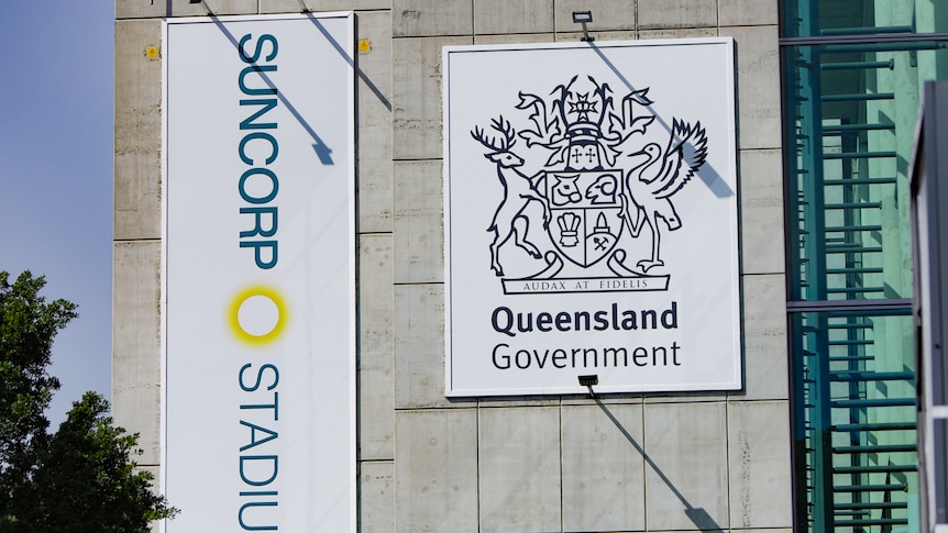 The Suncorp Stadium logo and the Queensland Government logo on banners hanging on the conrete wall of the stadium. 