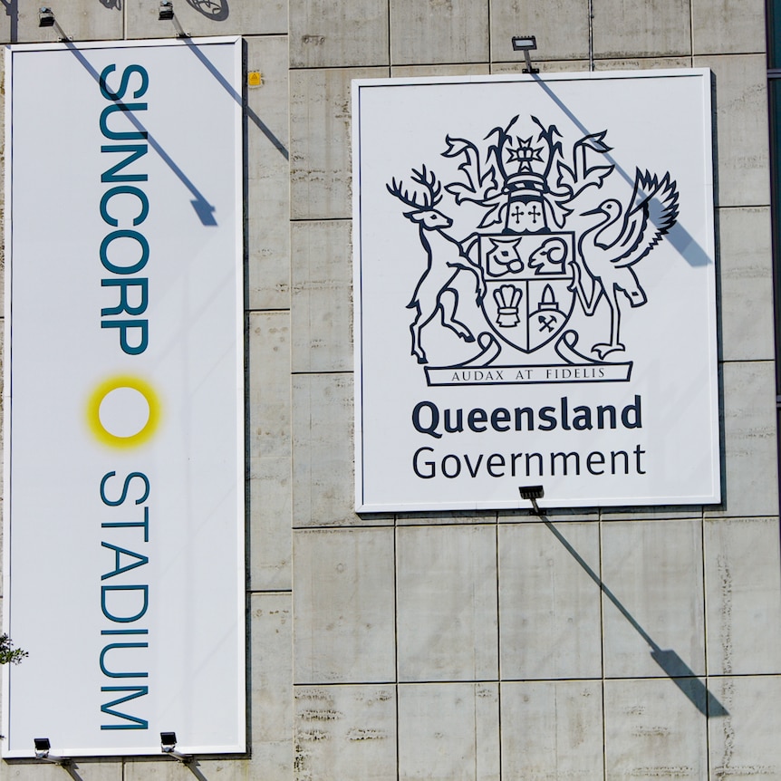 The Suncorp Stadium logo and the Queensland Government logo on banners hanging on the conrete wall of the stadium. 