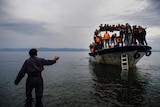 A Greek man talks to asylum seekers arriving by boat.