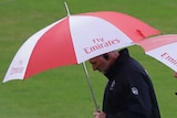 Umpires walk across the field with umbrellas